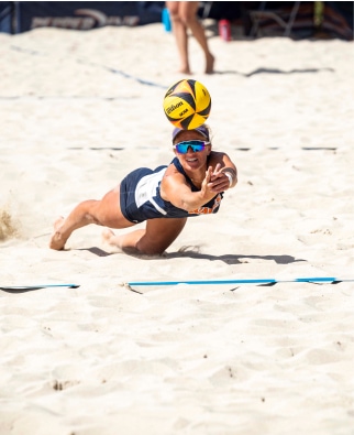 A beach volleyball player diving for a ball